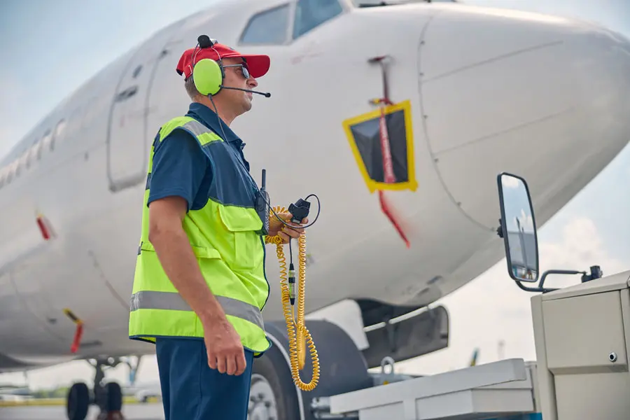 an air field employee with headphone standing by an airplane