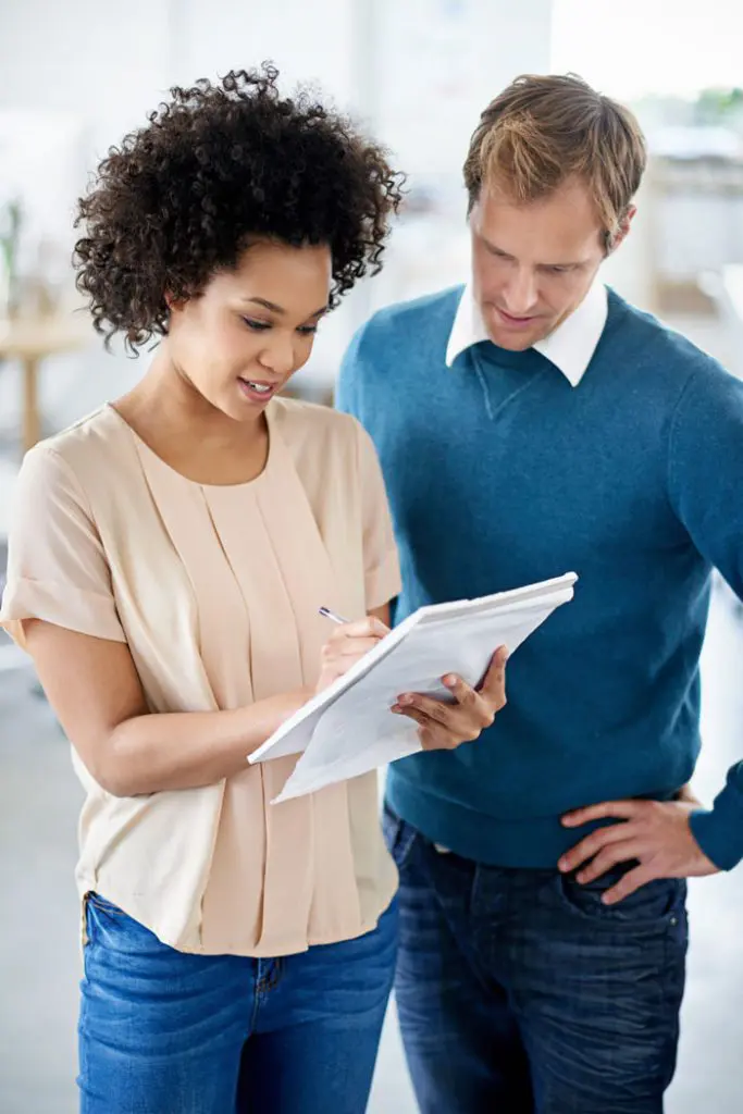 a man and woman are checking taking notes.