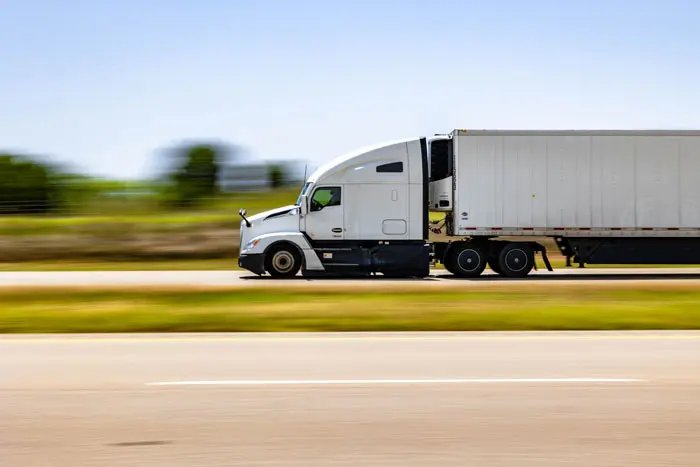 a picture of a semi-truck with a full load driving on highway