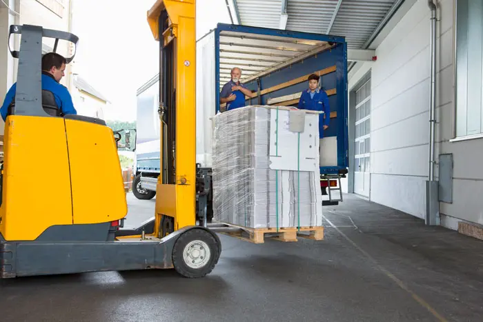 a forklift operator loading pallet in truck