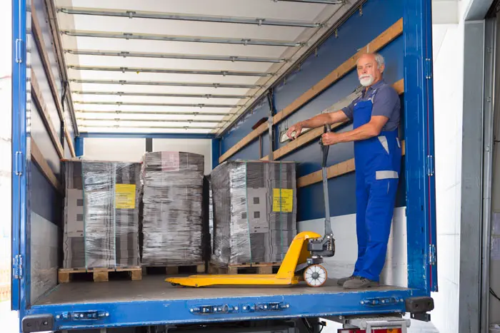 a mature employee loading pallets with a pallet jack