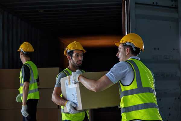 3 employees with hard hats passing parcels to each other