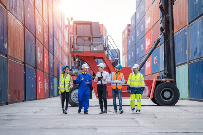 a group of shipping c\yard employees walking and talking to manager