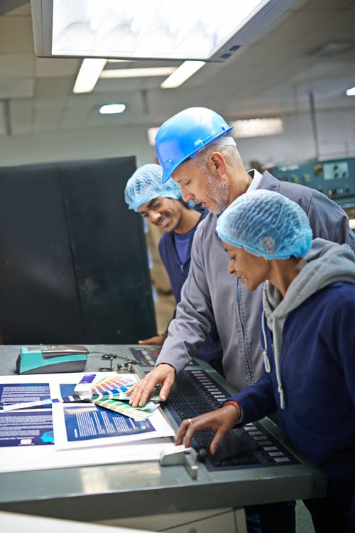 a group of employees standing by a desk and reviewing something