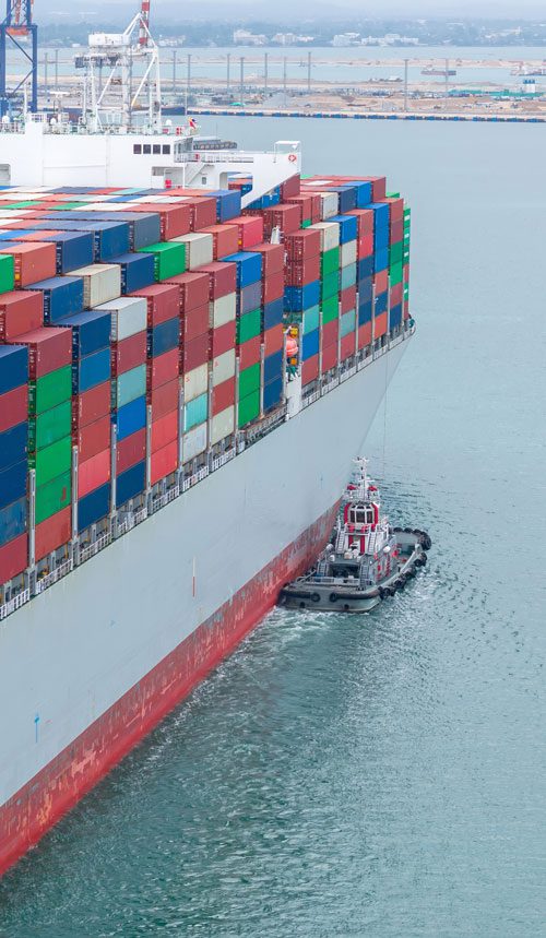 a container ship being shepherd to port by smaller boat 