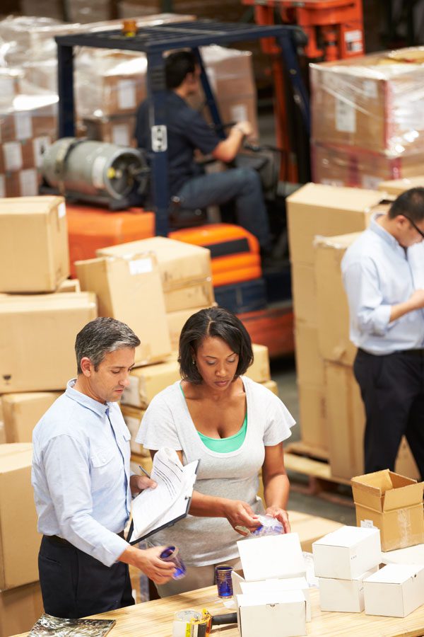 an employee and a manager are reviewing products in warehouse