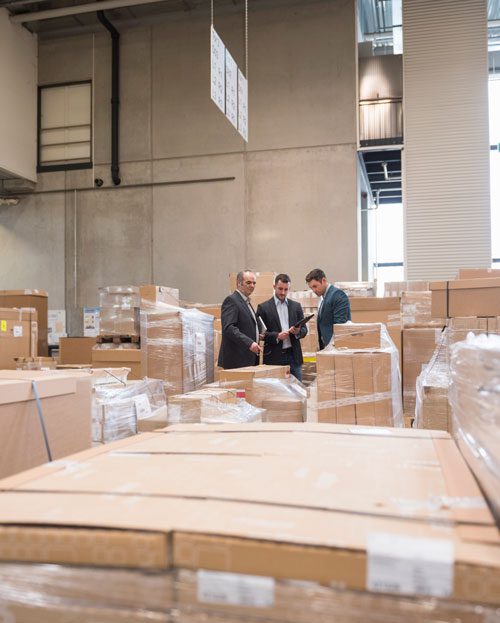 3 men in a warehouse of cargo